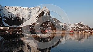 Reflection in the water. Snowy mountains, fishing village, red rorbu houses, and their peaceful reflections on the water