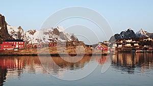 Reflection in the water. Snowy mountains, fishing village, red rorbu houses, and their peaceful reflections on the water