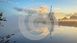 Reflection of White wooden windmill in river