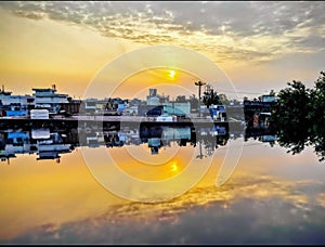 Reflection of whole city in pond with beautiful open and yellow sky photo