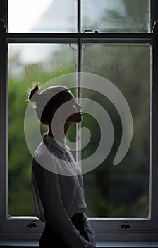 Reflection by the window. A beautiful young woman standing by a window.