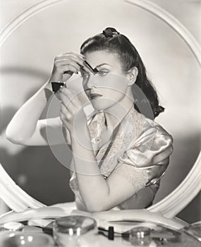 Reflection of woman in mirror applying eye make-up
