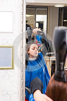 Reflection of Woman in Salon Blow Drying Hair