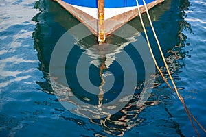 Reflection of a wooden fishing boat in water