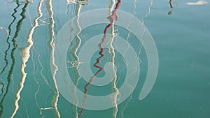 Reflection of yacht masts on the sea water of a marina