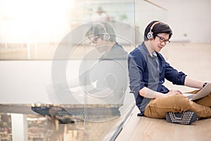 Young Asian business man listening to music while using laptop