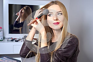 Reflection of young beautiful woman applying her make-up