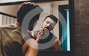 Reflection of young man in bathroom mirror looking on his face