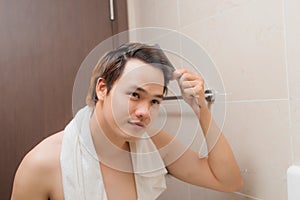 Reflection of Young Man Bushing Hair in Mirror