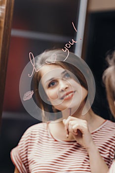 Reflection of young woman face in mirror with inscription