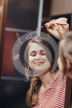 Reflection of young woman face in mirror with inscription