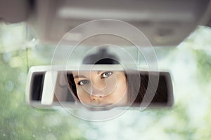 Reflection of young woman with frightened eyes covering her face with  hands in the car rear view mirror. Concept of an accident o