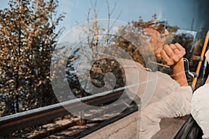 A reflection of a young woman traveling in a bus, looking at nature through the window. Travel alone concept, public transport,