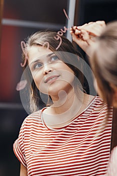 Reflection of young woman writing with cosmetic pencil words