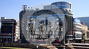 Reflections of city center in glass windows of modern big Telekom building in Skopje on sunny summer day