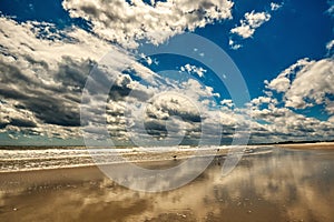 Reflections of a cloudy sky in the edge of the surf on a Carolina beach.