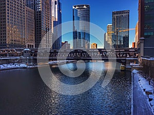 Reflections of downtown Chicago Loop on the river water in morning during winter.