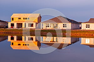 Reflections of new houses, being built on shoreline of a lake
