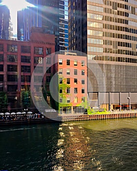 Reflections paint designs from nearby architecture onto Chicago River during summer evening while patrons enjoy happy hour