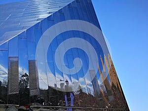 Reflections on side of modern glass structure against blue sky
