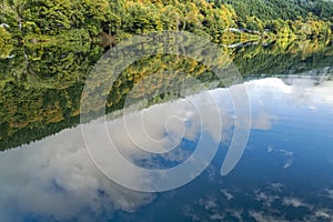 Reflections of the sky and autumn foliage in the Umpqua River at Scottsburg, Oregon, USA