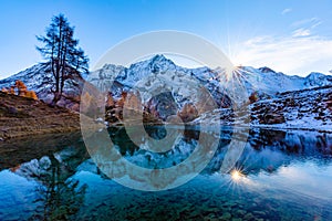 Reflections of snow capped mountains in a blue icy lake in the mountains