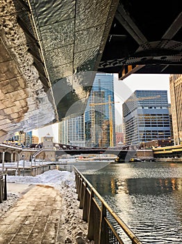 Reflections of snow covered Chicago Loop along the riverwalk of the Chicago River underneath a bridge in the Loop. photo
