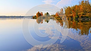 Reflections of stunning autumn forest and sky on rippling lake surface