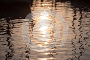 Reflections of sun and masts of a sailing vessel on the waterr
