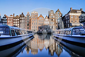 Reflections of traditional dutch houses and tourist canal boats