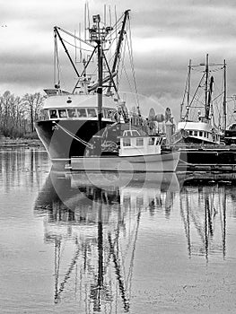 Reflections of vessels tied up at a fishing pier