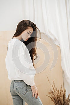 Reflective beautiful woman wearing tight jeans and white shirt.