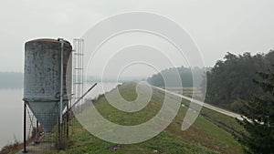 Reflective misty lake on an early autumn morning with a large metal silo, aerial