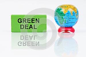 On a reflective surface is a globe and a green sign with the inscription - Green Deal