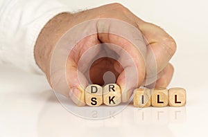 On the reflective surface in the hands of a man are cubes with the inscription - Drill or skill