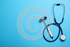 Reflex hammer, stethoscope and space for text on light blue background, flat lay. Nervous system diagnostic