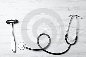 Reflex hammer with stethoscope on white wooden background, flat lay. Nervous system diagnostic