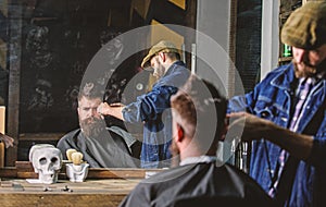 Reflexion of barber with clipper trimming hair of client. Hipster client getting haircut. Barber with hair clipper works