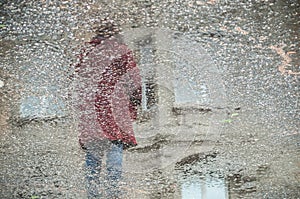 Reflexion of woman in puddle in the street