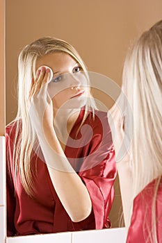 Reflexion of young blone woman removing make-up