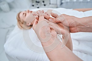 Reflexologist applying pressure to the acupoint on the woman palm