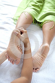 Reflexologist giving woman client a foot massage photo