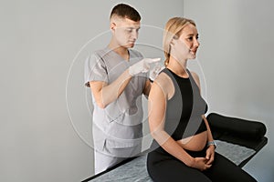 Reflexologist performs an acupuncture session on a pregnant woman