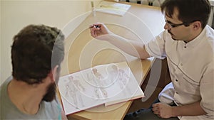 Reflexologist receives patient explaining him purpose of acupuncture points.