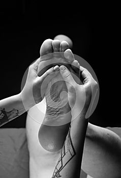 Reflexology foot massage. Physiotherapist massaging male patient with injured leg muscle, closeup.