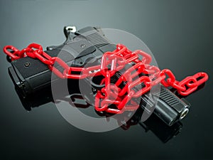 Reform gun control concept. red chain around handgun on black