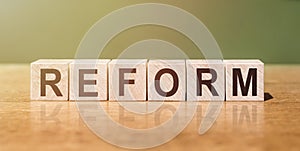 Reform word in Wooden cubes on a green-brown background