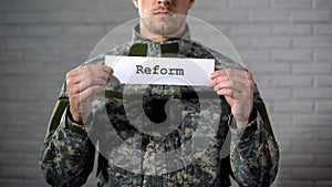 Reform word written on sign in hands of male soldier, military law amendment