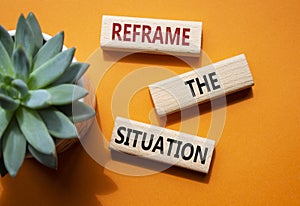 Reframe the situation symbol. Concept words Reframe the situation on wooden blocks. Beautiful orange background with succulent