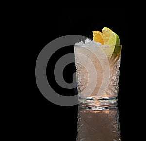 Refreshing alcoholic cocktail with crushed ice and citrus fruits on black background